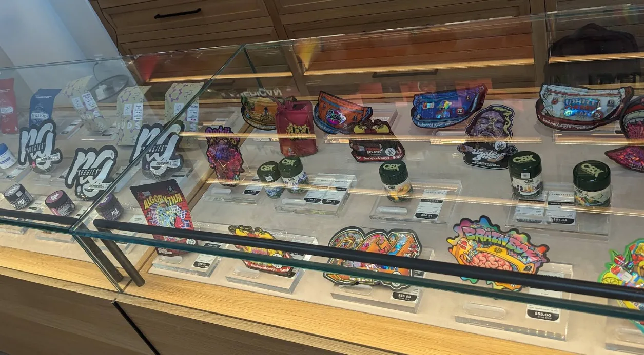 Home 15 A flower case at Caña Beverly, mylar pouches and glass jars on a lit shelf