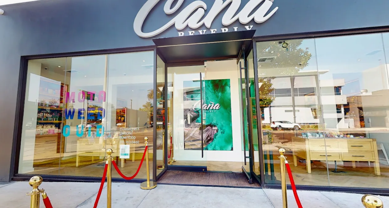 Home 70 The entrance at Caña Beverly, glass doors behind gold stanchions and a red rope